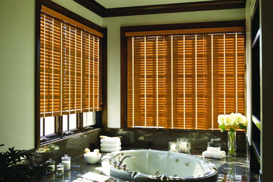 Premium quality blinds are always a stylish accent in your Southern California home. Brown wood blinds on large windows in a green bathroom