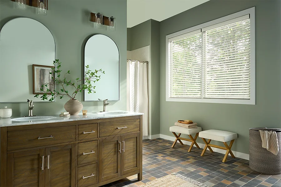 White faux-wood blinds cover a large bathroom window