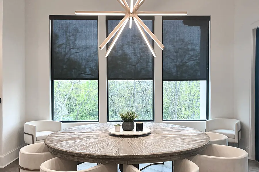 black motorized shades in three tall windows at a dining room area