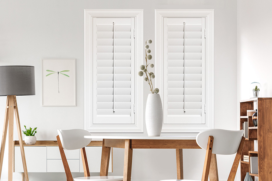 Sunburst's selection of stylish window treatments for designers in Southern California makes it easy to find the perfect ones for every design job. White Polywood shutters on two windows in a modern Scandinavian-style room
