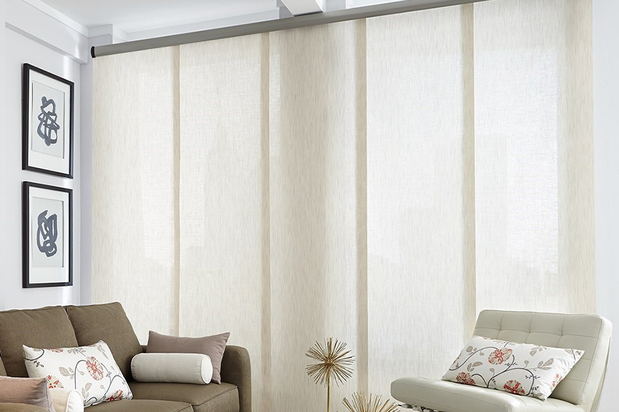 Find window treatments to complete any interior design among our extensive selection at Sunburst Shutters Southern CA. Long off-white window shades on a tall window in a modern living room