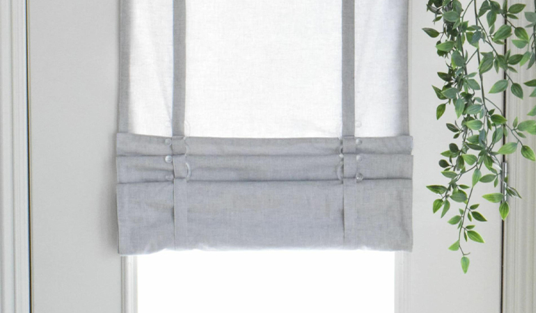 With a tiered tumble shade in Southern California, you can block sun glare all year round. Gray rolled tumble shade on a glass door