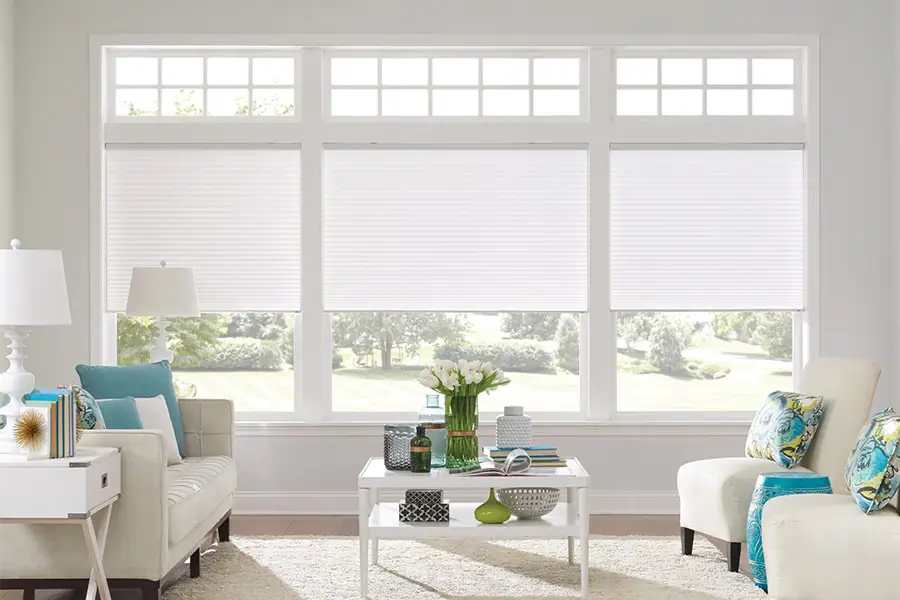 Insulating cellular shades can help keep cold air and hot UV rays from entering your Southern California home. White cellular shades on windows in a white living room